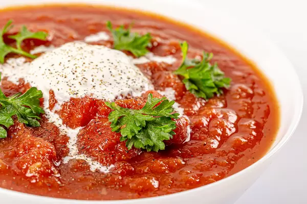 Bowl with tomato soup and fresh parsley leaves, close-up