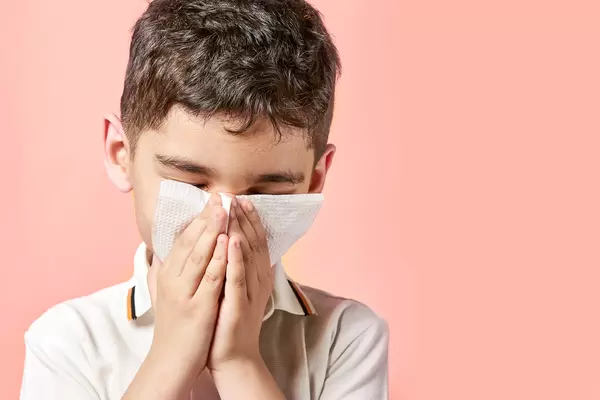 Boy with a tissue blowing his nose