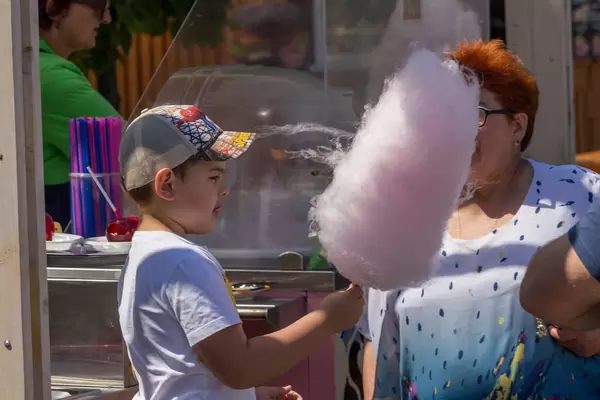 Boy with cap eating cotton candy