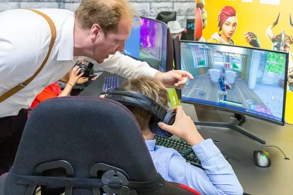 Boy with headphones plays Fortnite on a curved screen