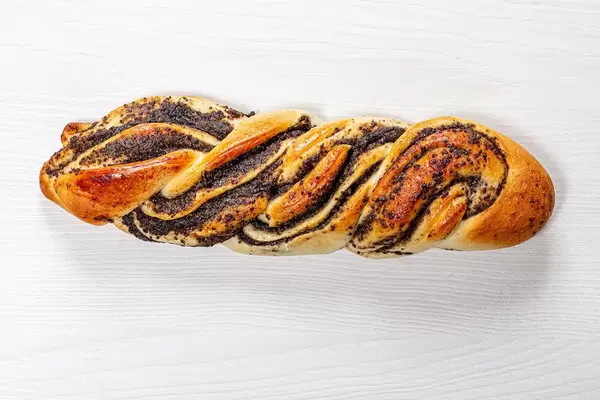 Braided bun with poppy seeds on white wooden background (Flip 2019)