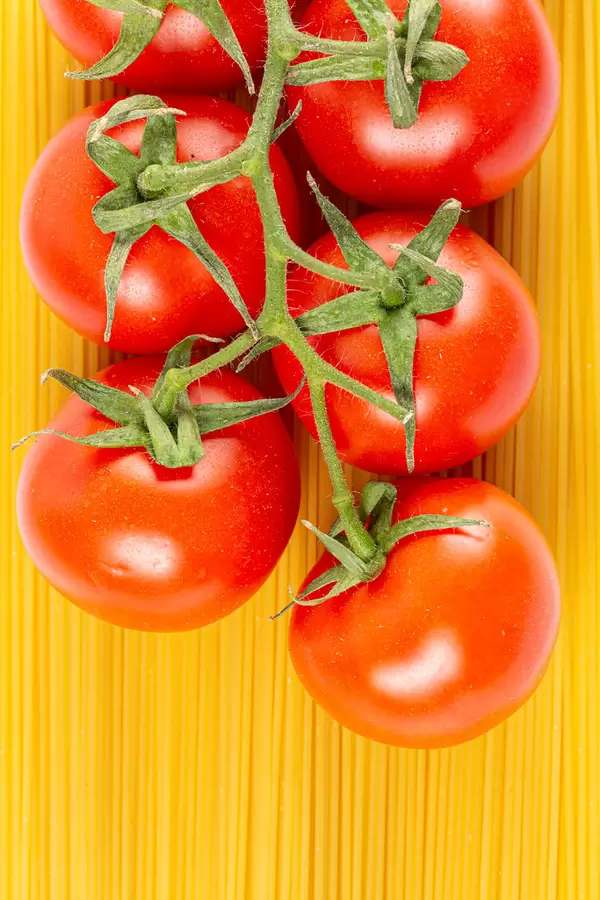 Branch of cherry tomatoes on a background of raw spaghetti