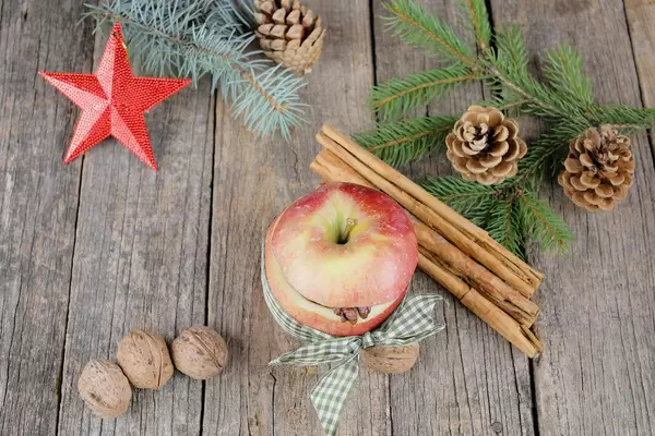 Bratapfel als deutsches Gericht umgeben von Zimt, Zweigen und Walnüssen