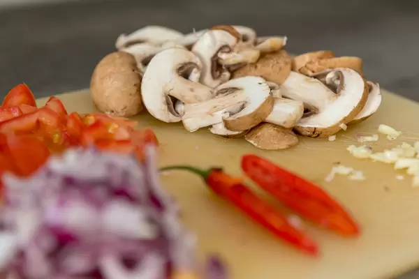 Braune Champignons in Scheiben - Bokeh mit Chili und Zwiebeln im Vordergrund