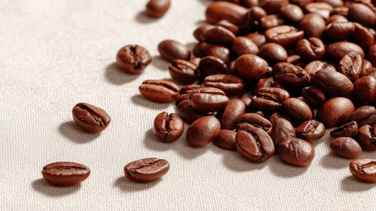 Braune Kaffeebohnen verstreut auf beiger Oberfläche