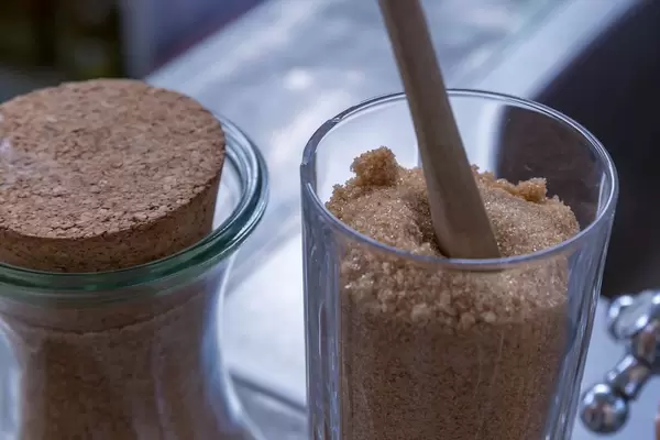 Brauner Zucker in einem Glas mit einem Holzlöffel