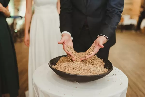 Brautpaar steht vor einer Schüssel Gerstensamen auf einem Hochzeitsritual