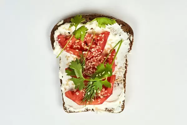 Bread slice with spread sour cream, tomato and parsley