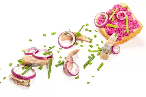 Bread with horseradish, onions and pieces of herring on white, the concept of making a sandwich