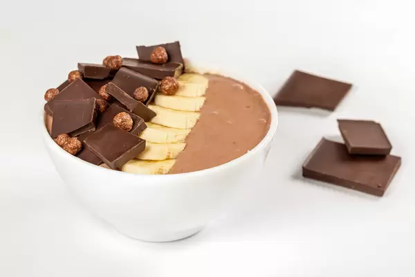 Breakfast background-bowl of oatmeal with banana, chocolate and yogurt