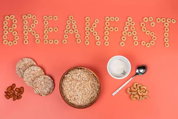 Breakfast background with a bowl of oatmeal, nuts and cottage cheese on a pink background