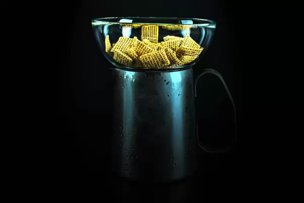 Breakfast cereals in a glass bowl on a metal jug full of milk
