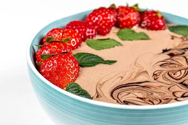 Breakfast concept, oatmeal with strawberry slices, mint leaves and chocolate yogurt