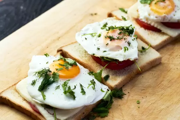 Breakfast for three people at home, fried eggs with toast, mozzarella and tomatoes