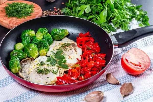 Breakfast in the pan-fried eggs with vegetables and herbs on the table (Flip 2019)