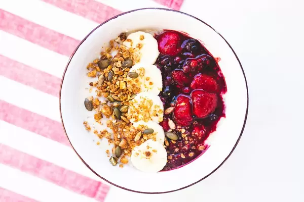 Breakfast oatmeal bowl with granola, bananas and jam on top