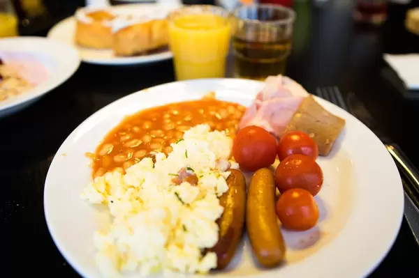 Breakfast plate with eggs, sausages, beans, and tomatoes