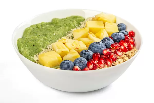 Breakfast porridge with blueberries, pomegranate, pineapple pieces, sesame seeds and fruit puree