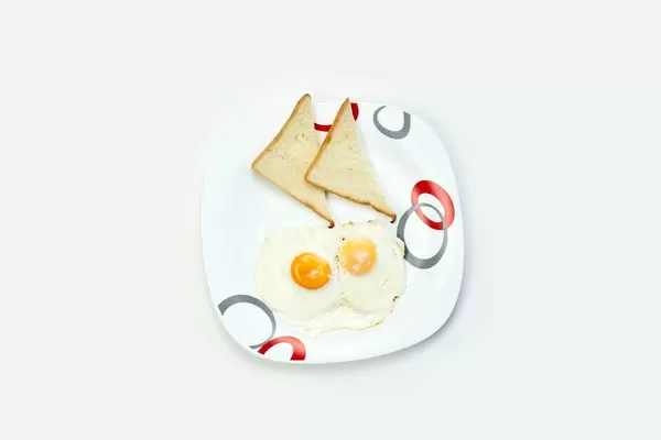 Breakfast with eggs and toasts on white table