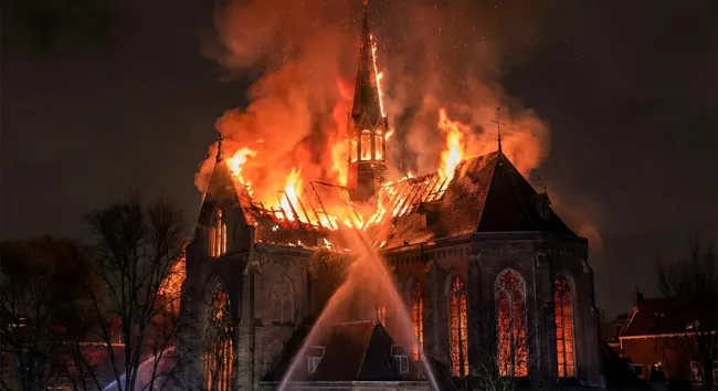 Brennende gotische Kirche bei Nacht mit Feuerwehreinsatz