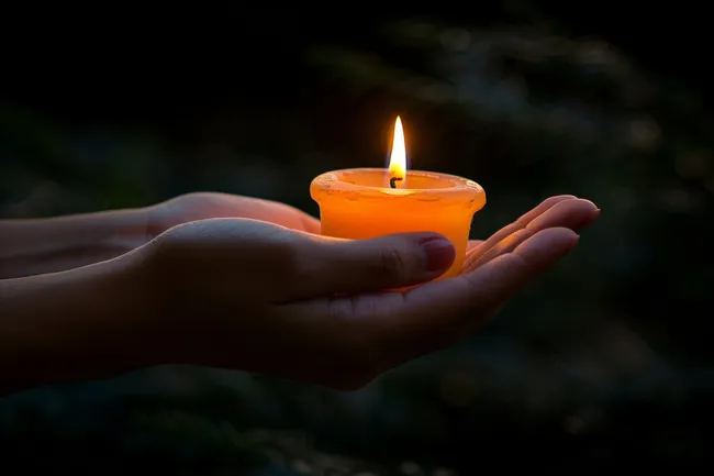 Brennende Kerze in Hand gehalten