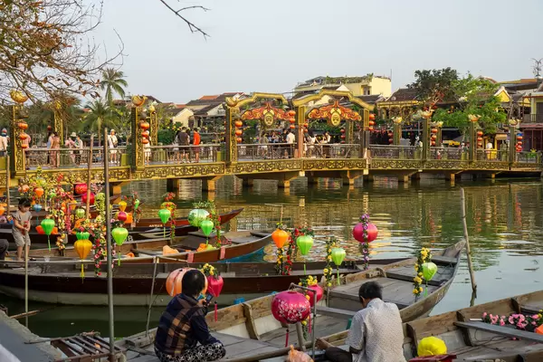 Bridge of Light crossing the Thu Bon River with many Tourist Boats decorated with colorful Lanterns in the Ancient Town of Hoi An, Vietnam