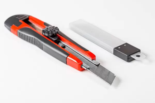 Briefpapiermesser und Packung von Klingen auf weißem Hintergrund