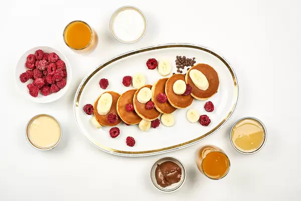 Bright breakfast table with pancakes, fruits, chocolate and honey