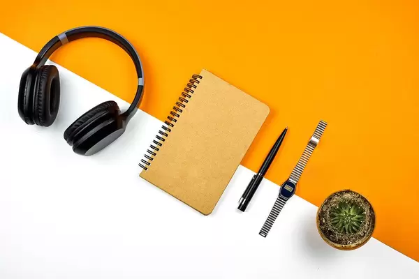 Bright workspace. Wireless headphone, notepad, wristwatch and cactus from above