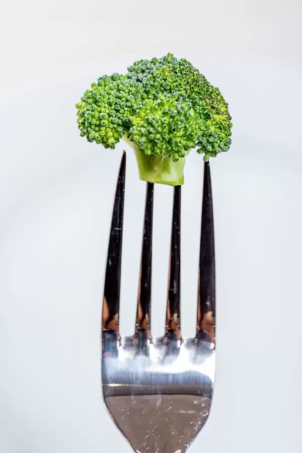 Broccoli on fork on white background