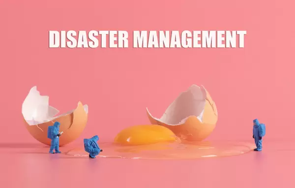 Broken brown chicken egg with miniature workers in protective clothes and Disaster Management text