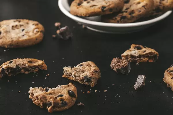 Broken cookies with pieces of chocolate on a black background (Flip 2019)