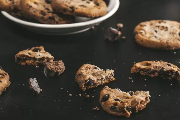 Broken cookies with pieces of chocolate on a black background