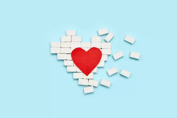 Broken heart made of sugar cubes on blue background