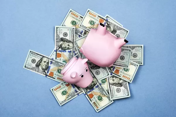 Broken piggy bank on a pile of US dollars