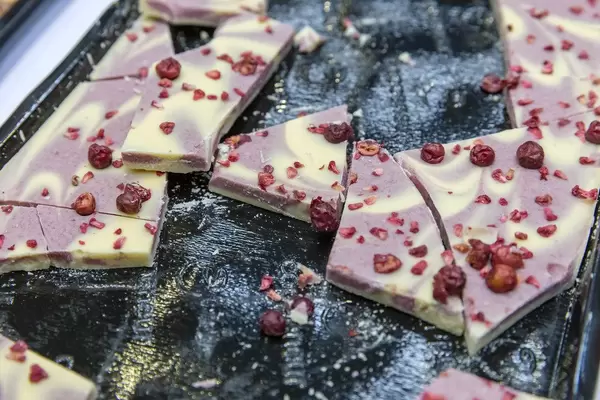 Broken Yoghurt and forest fruit chocolate with rasp berries, on a black tray