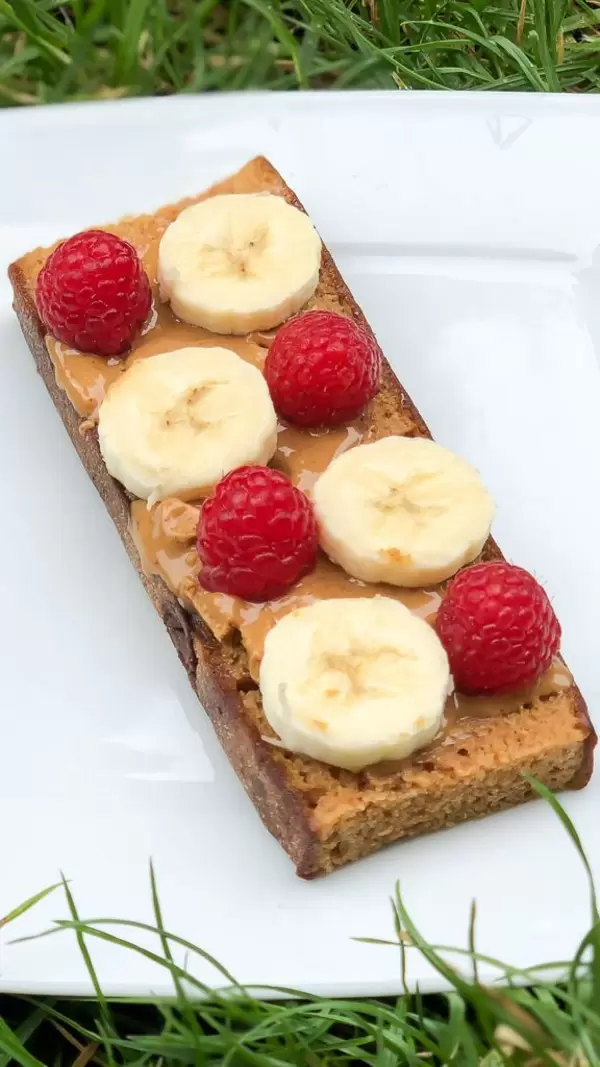 Brotscheibe mit Erdnussbutter, Bananen und Himbeeren