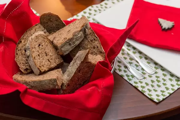 Brotscheiben in auf roter Serviette in Korb vor weihnachtlich gedecktem Tisch
