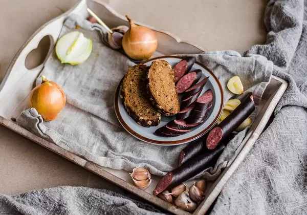 Brotzeit mit frischer Wurst, Zwiebeln und Knoblauch auf Holztablett