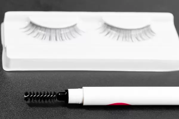 Brow brush and false eyelashes on a black background