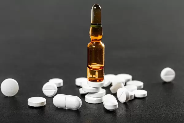 Brown ampoule and white tablets on a dark background