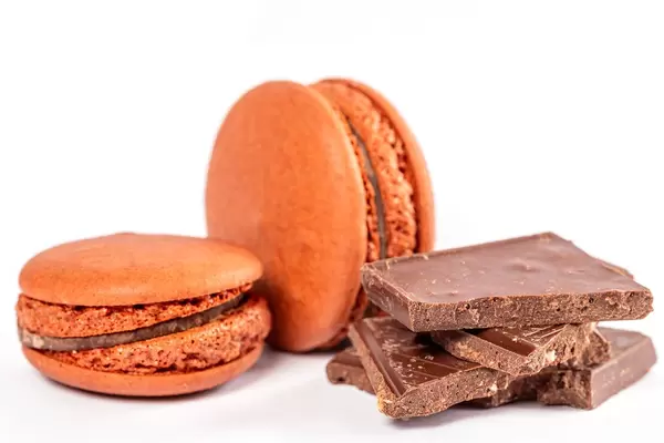 Brown macaroon dessert with chocolate pieces on a white background