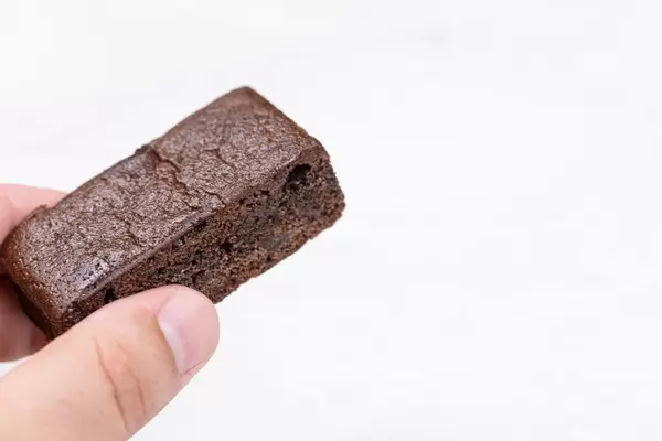Brownie cookie in the hand with copy space above white background