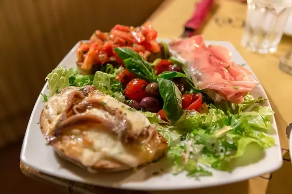 Bruschetta mit Sardinen, Proscciutto und Tomaten auf Salat mit Oliven und Basilikum in Mimi e Cocos Weinbar in Rom