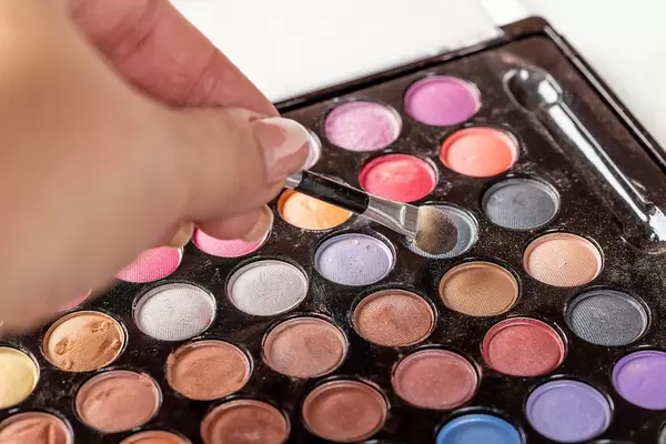 Brush in girl's hand, uses eye shadow