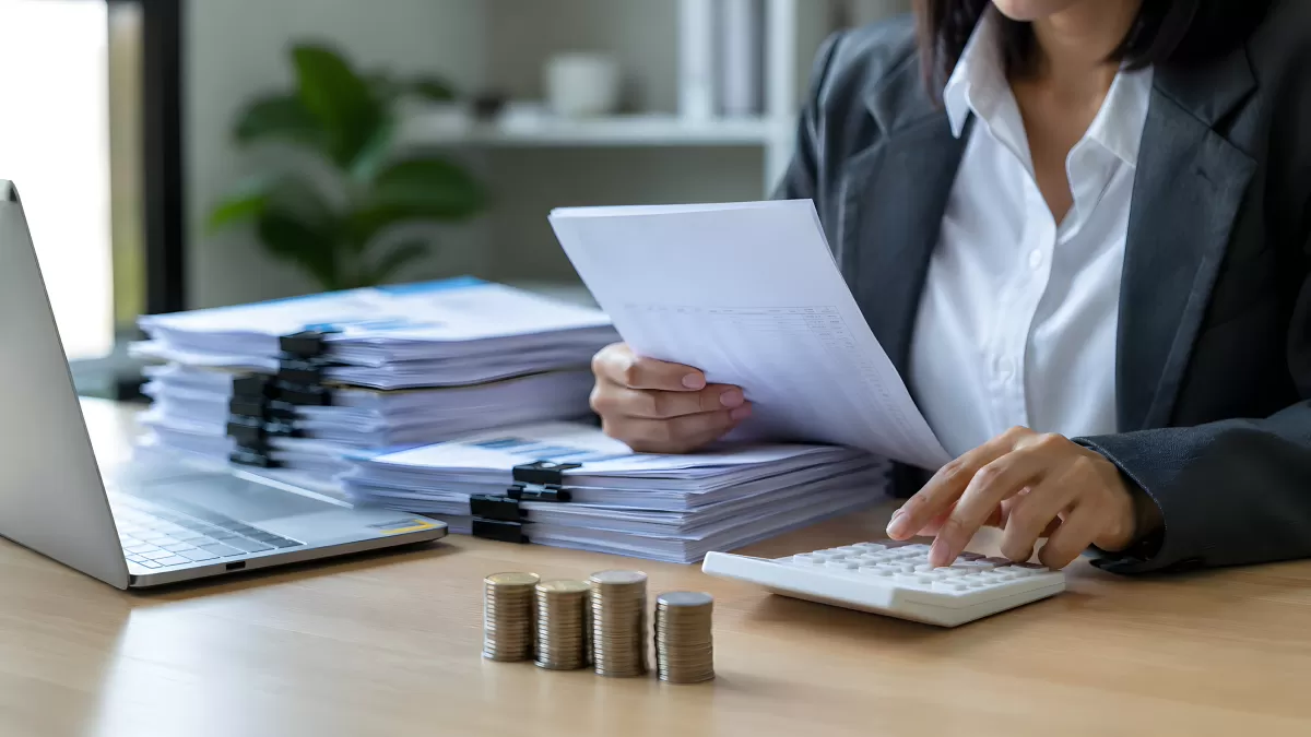Buchhalterin prüft Dokumente mit Taschenrechner im Büro