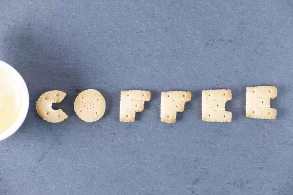 Buchstaben formen aus Biscuit neben einer Kaffeetasse