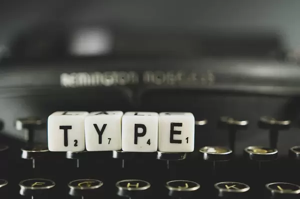 Buchstabenwürfel legen das Wort "Type" und liegt auf einer Retro-Knopftastatur