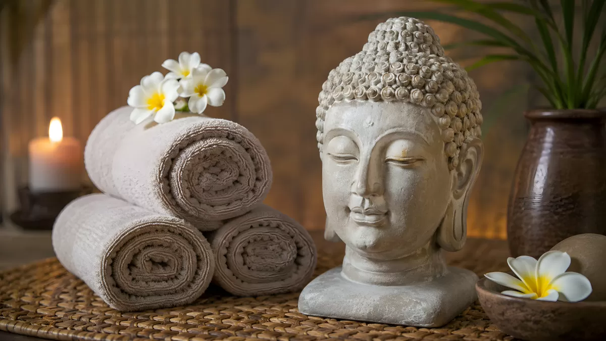 Buddha-Statue mit Handtüchern und Blumen im Spa