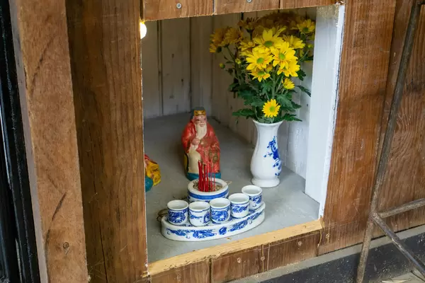 Buddhist Shrine with Flowers, Liquor in Ceramic Cups and a Small Statue of the God of Money at a Cafe in Vietnam